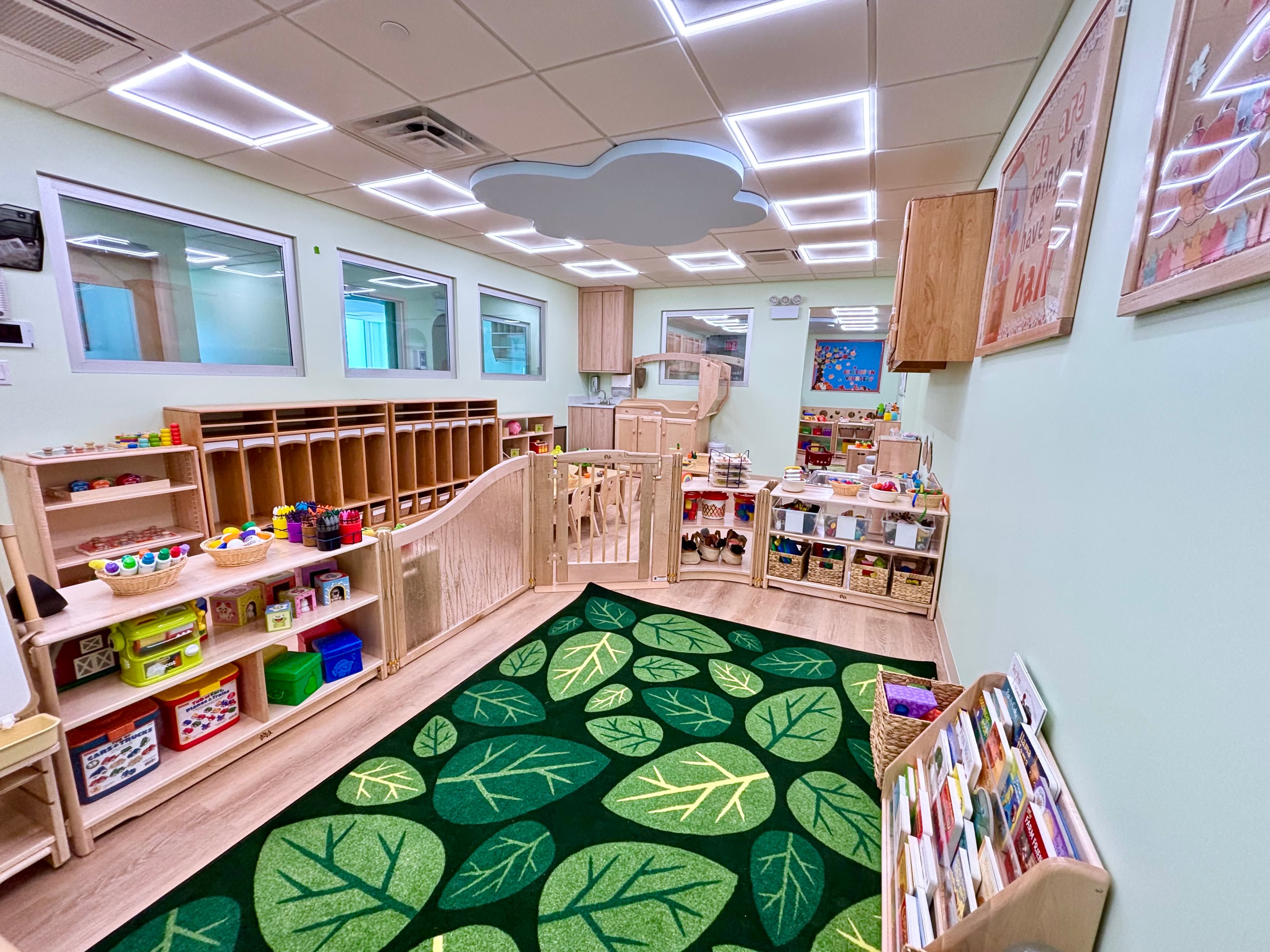 Organized Greenpoint classroom with open shelves, Montessori materials, and a leaf-patterned rug