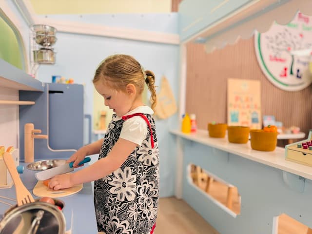 Pre-K child cooking at the dramatic play kitchen, practicing planning and independence