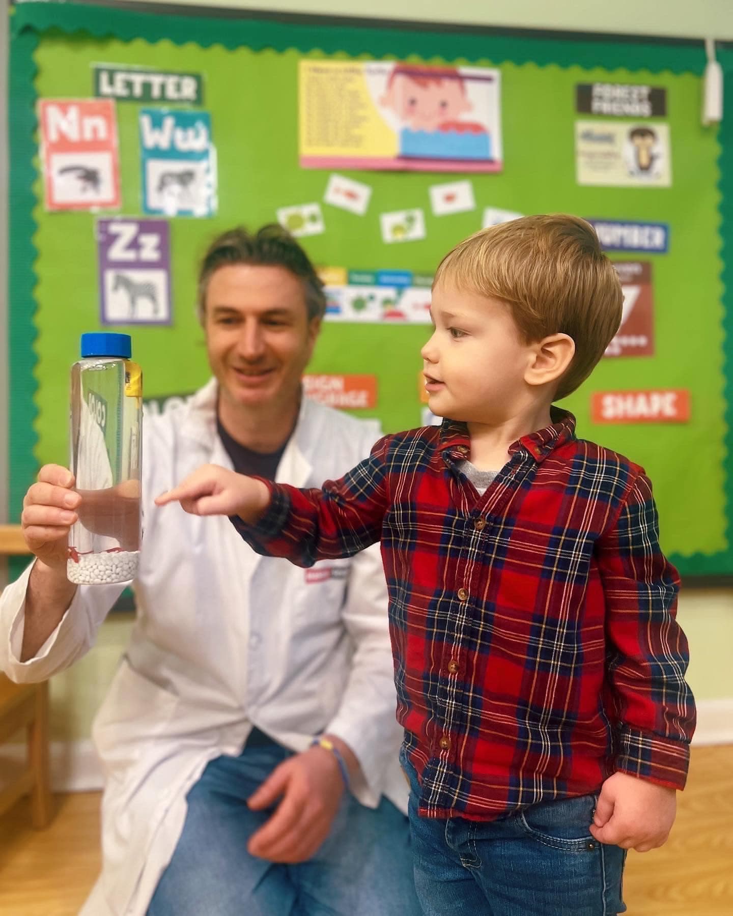 Preschooler examining a sensory bottle with a science specialist at Kinder Prep
