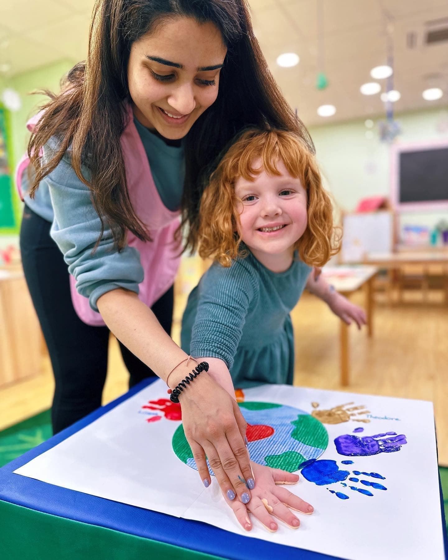 Teacher and preschooler making a collaborative Earth handprint art project