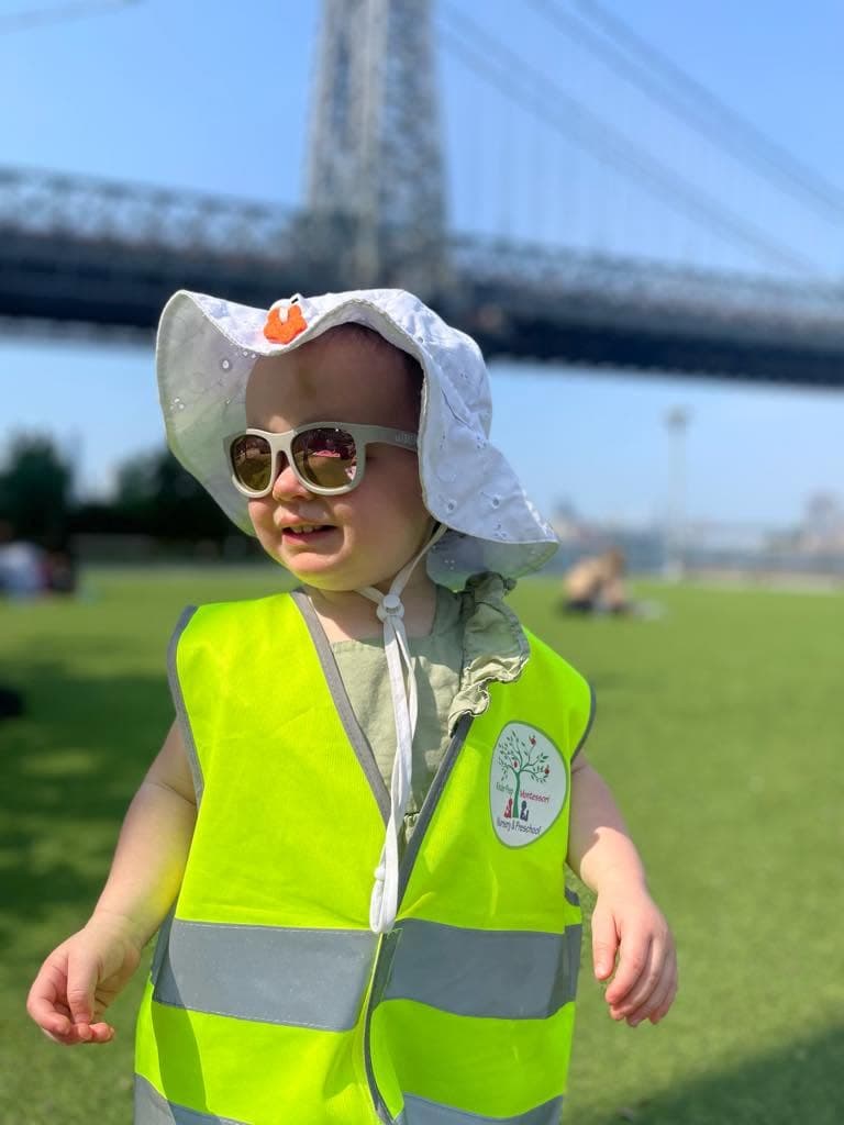 Young Kinder Prep camper in a safety vest on a park outing near the Williamsburg Bridge