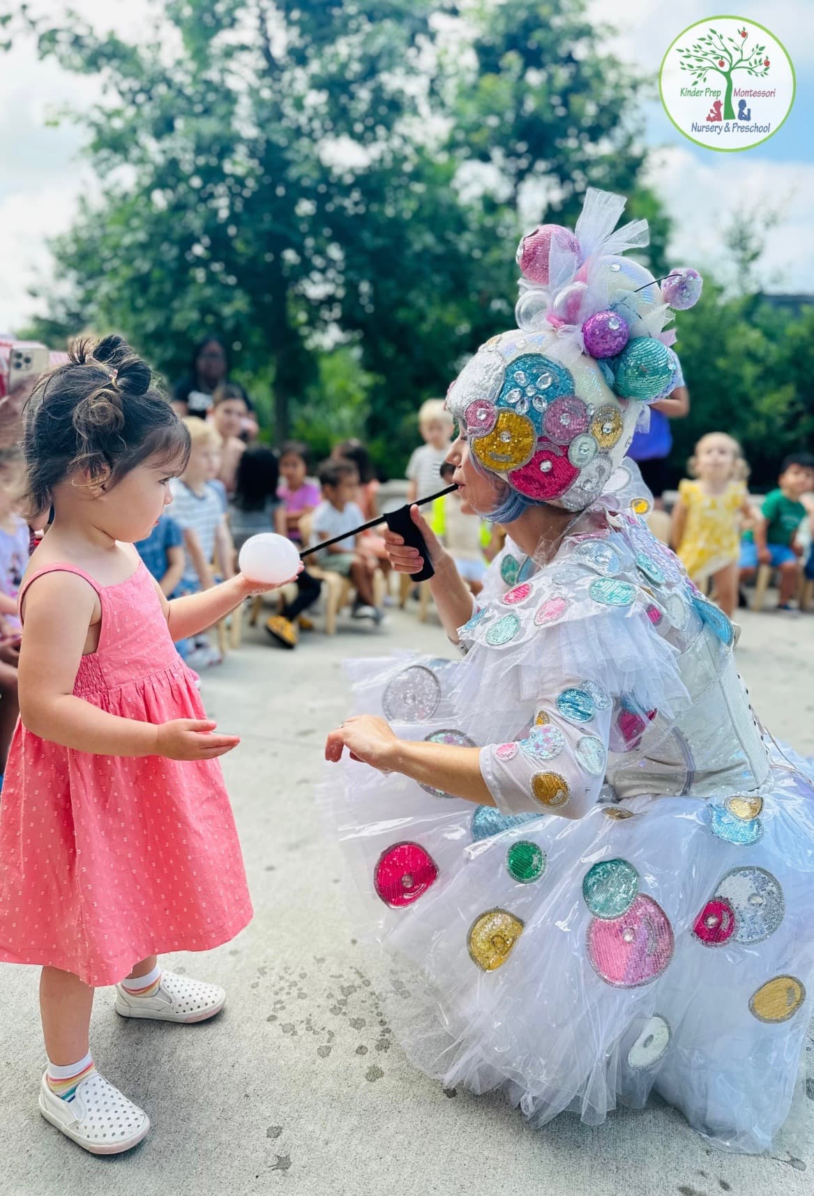 Toddler in a summer dress meeting a sparkly bubble performer at an outdoor summer event