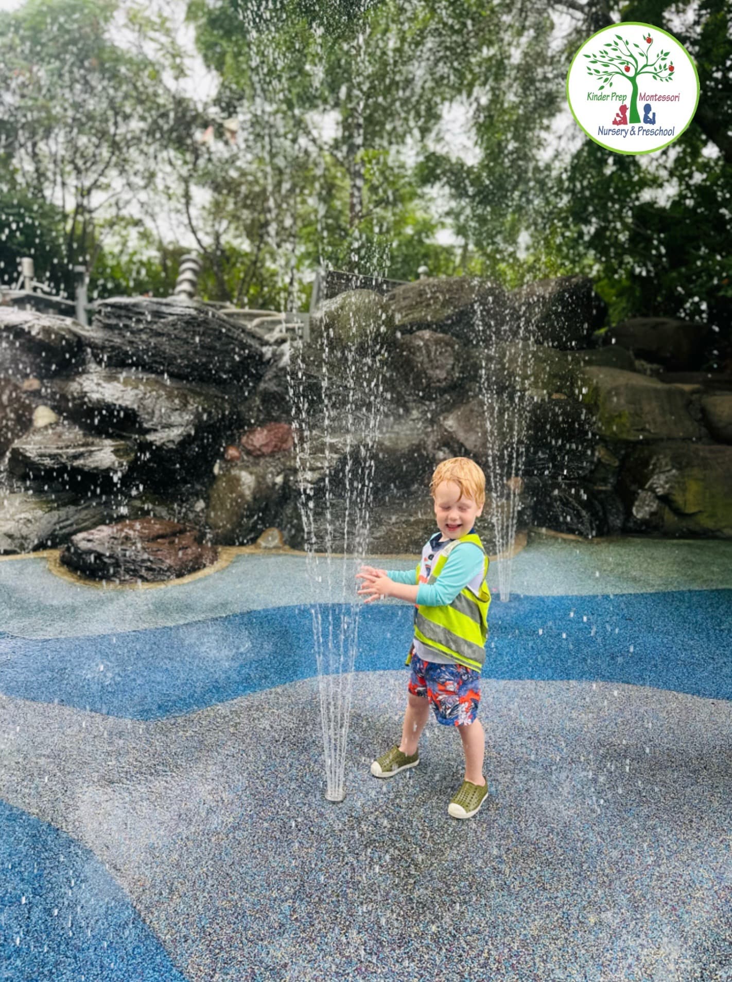Kinder Prep camper laughing in the water jets at the Pier 6 Water Lab splash pad in Brooklyn Bridge Park