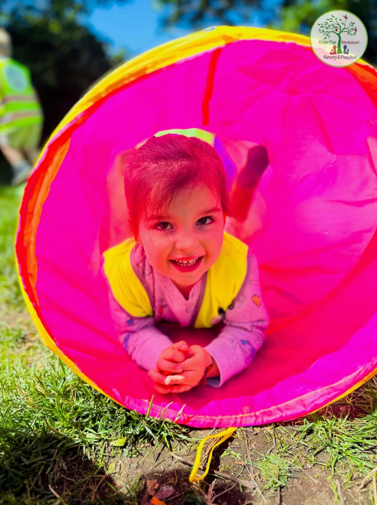 Smiling camper crawling through a bright play tunnel on the grass on a sunny summer day